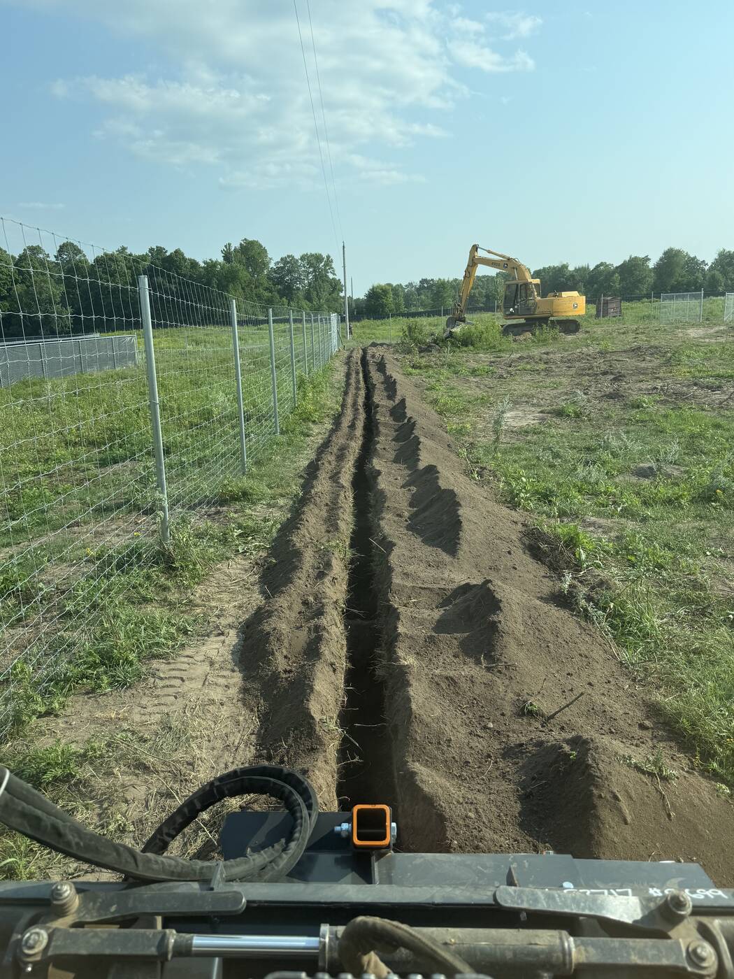 Long open utility trench running along a fence line in Long Prairie, MN
